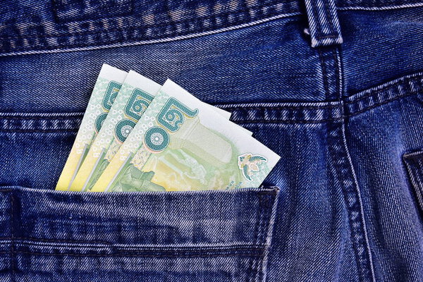 Thai money in the back pocket of jeans. Concept on a trip to Thailand. Concept on a trip to Thailand, shopping for souvenirs