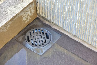 Shower drain box grate on a shower base. Sand and dirt on the floor. Cleaning required clipart