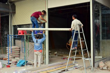 12 Temmuz 2018. Nha Trang. Vietnam. Gerçek işçi roller kepenkler yükleyin. değil hazırlama sahne. Kullandıkları bir merdiven ve iskele