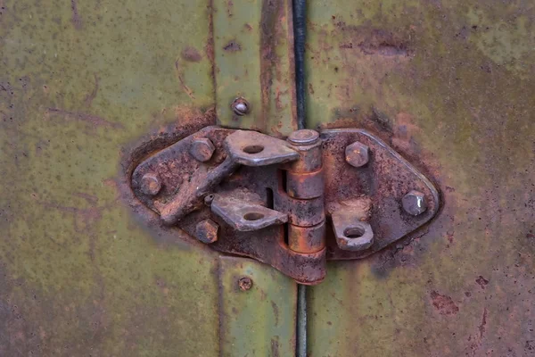 Rusty door hinge of an old military car. In the hinge there are holes for fixing the door in the open position