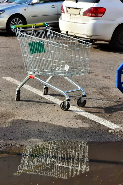 Alışveriş sepeti arabası süpermarket. sol yanındaki su birikintisi Park yerinde. çamura yansıyan