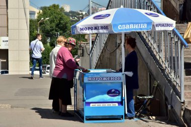 1 Ağustos 2018. Krasnoyarsk. Rusya. İki yaşlı kadın dondurma sokak bir dükkanda satın. Dükkanı bir şemsiye ile kaplıdır