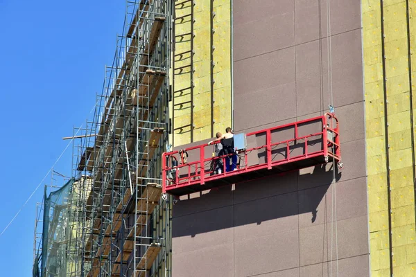 グラスウール断熱の外壁の高度作業 労働者が建物のファサードを絶縁し パネルでそれを終える特別な機器を使用します — ストック写真