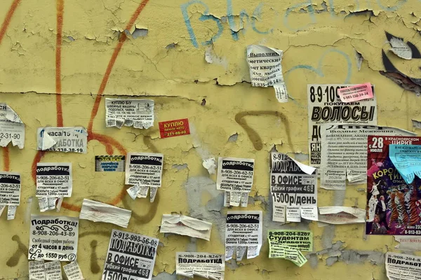 Krasnoyarsk. Rusya. 3 Ağustos 2018: bülten panosu yaşıyorum. Paramparça bir eski sarı duvar çeşitli reklam