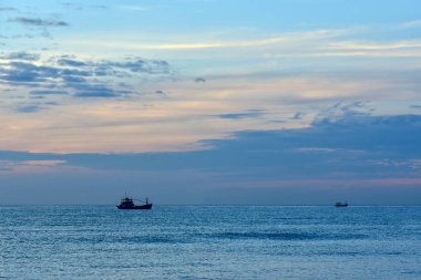 Küçük bir balıkçı teknesi günbatımı çerçevede bir silüeti