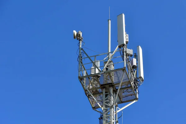 Cellular antenna tower against blue sky. Top of steel mast. copy space for text