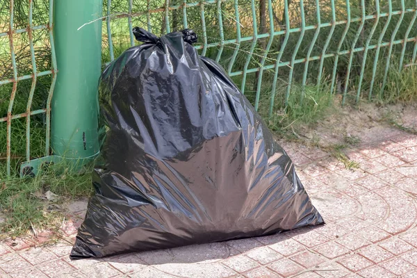 Zwarte Vuilniszak Naast Groene Hek — Stockfoto