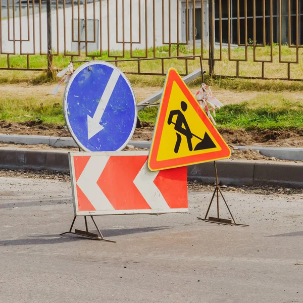 Work in progress. Roadworks, road signs. Men at work. Some signs signage for work in progress on urban street. left arrow.