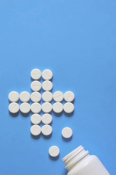 白い錠剤は十字の形にレイアウト 白い錠剤は青い背景に散在しています 薬瓶からこぼれた コピーのテキストのための領域 — ストック写真
