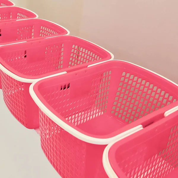 A row of empty pink baskets in the store