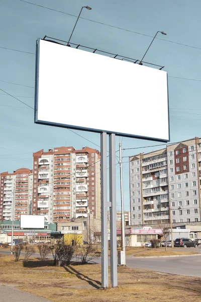 Grand panneau d'affichage dans la ville parmi les bâtiments contre ciel nuageux bleu. Maquette pour votre publicité ou annonces — Photo