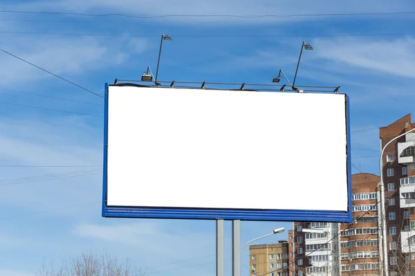 Большой рекламный щит в городе среди зданий против голубого облачного неба. Подготовьте макет для рекламы или объявлений — стоковое фото