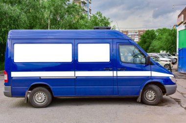 Yeşil ağaçların arka plan üzerinde otoparkta Mavi kargo minibüsü. metin reklamlarınız için kopya alanı sahte