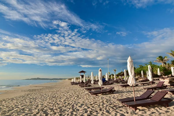 Sun loungers and umbrellas on an empty sandy beach. Summer sunny cloudy blue sky. Kamran. Vietnam. Copy space for text — Stock Photo, Image