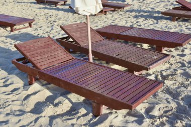 Kumlu bir plajda boş ahşap şezlong yakın çekim