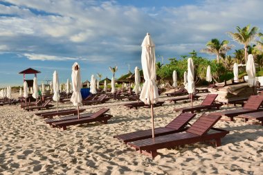 Boş bir kumsalda şezlonglar ve şemsiyeler. Yaz güneşli bulutlu mavi gökyüzü. Kamran mı? Vietnam.