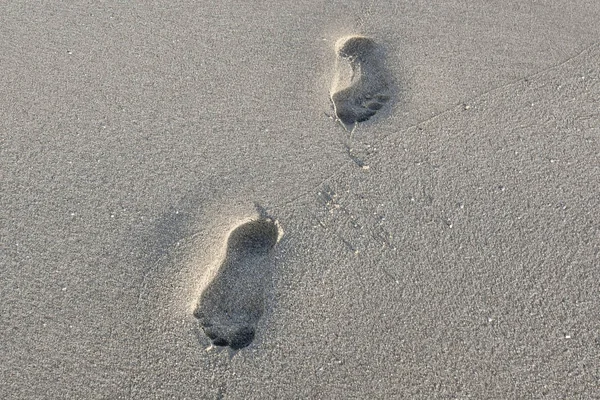 Gün batımında ince kum iki insan ayak izi — Stok fotoğraf