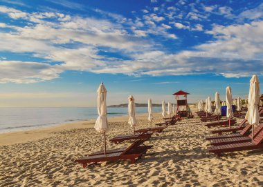 Boş bir kumsalda şezlonglar ve şemsiyeler. Yaz güneşli bulutlu mavi gökyüzü. Cam Ranh. Vietnam.