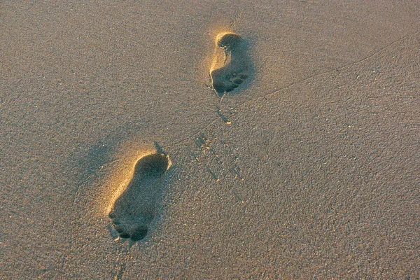 Gün batımında ince kum iki insan ayak izi — Stok fotoğraf