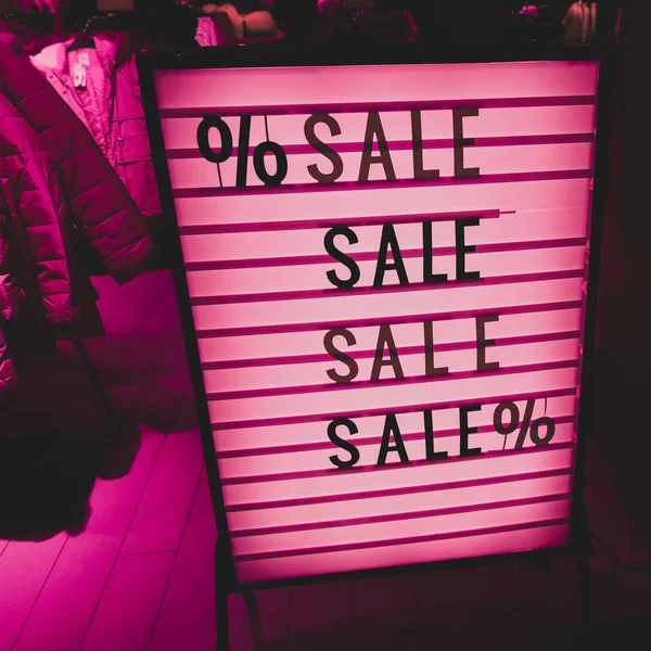 Stylish vintage sign. SALE in a showcase of a clothing store. Beautiful pink lights — Stock Photo, Image