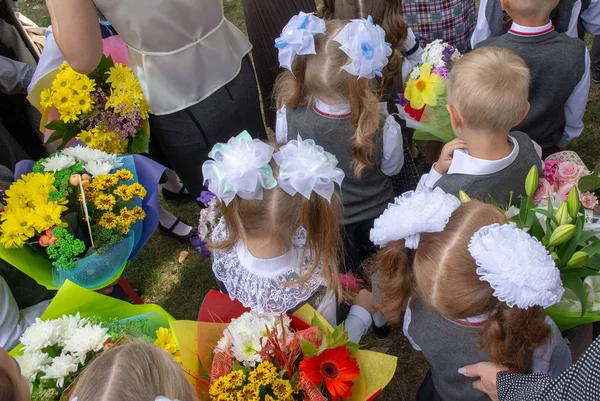 Krasnoyarsk. Rusya. ellerinde çiçek ve balon buketleri ile birinci sınıfa kayıtlı çocuklar, okul ciddi geçit töreninde öğretmenler ve lise öğrencileri