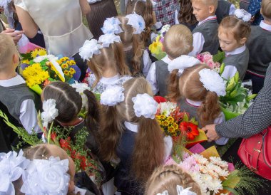 1 Eylül 2018. Krasnoyarsk. Rusya. ellerinde çiçek ve balon buketleri ile birinci sınıfa kayıtlı çocuklar, okul ciddi geçit töreninde öğretmenler ve lise öğrencileri