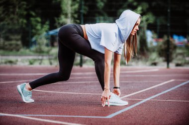 Çalıştırmak için hazır! Kadın atlet bir Bahçesi, başlangıç çizgisi üzerinde bir çalışma, yan görünümü için hazırlanıyor. Fitness kız düşük bir başlangıç çalıştırmak hazırlanıyor. Sağlıklı yaşam tarzı.