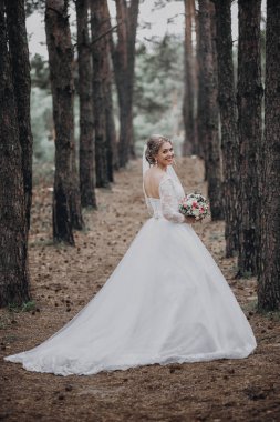 Bir güzel şehvetli Genç gelin uzun beyaz gelinlik ve ormandaki buket doğal zemin üzerine açık tutarak ayakta peçe tam uzunlukta yan görünüm