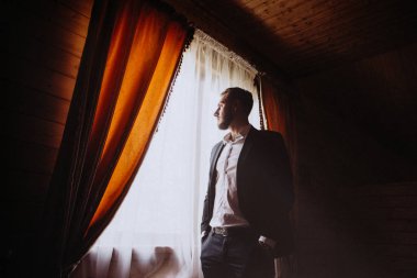 Genç ve güzel bir damadın ciddi portresi. Adam pencereden bakar, bir toplantıya hazırlanır..
