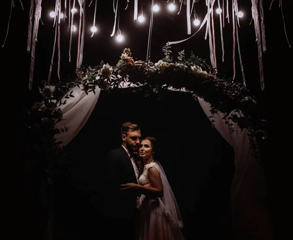 夢中になる新婚夫婦を優しく受け入れます 自然の中の結婚式 電気のガーランドの灯の結婚パーティー — ストック写真