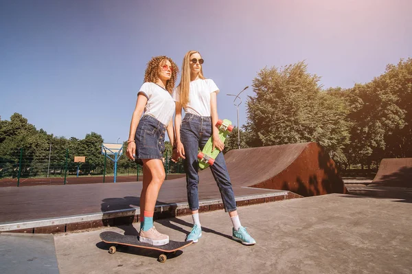 Kaykay ile paten parkta oynayan iki arkadaşlar. Gülme ve eğlence.