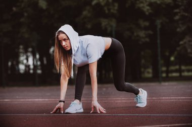Gitmek için hazır! Kadın atlet başlangıç çizgisine Stadyumu parçanın üzerinde bir çalıştırmak için hazırlanıyor. Fitness kız düşük bir başlangıç çalıştırmak hazırlanıyor. Sağlıklı yaşam tarzı.