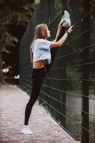 在公园健身训练之前 年轻女性锻炼 健康的年轻妇女在户外热身 她在伸展她的腿 — 图库照片