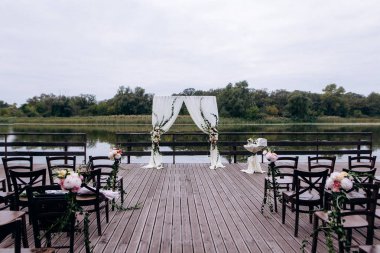 Giden düğün töreni. Dekor Studio. yeşil çim üzerinde kahverengi ahşap sandalyeler. Düğün bayram arch. Konuklar için beyaz koltuklar