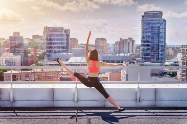 运动女孩做瑜伽和普拉提在摩天大楼的屋顶上 — 图库照片