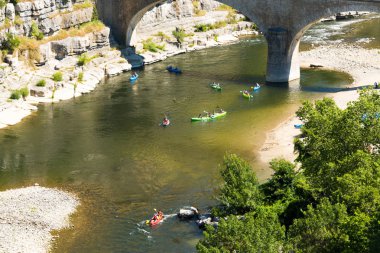 Canoeists on the river Ardeche under the old bridge near Balazuc clipart
