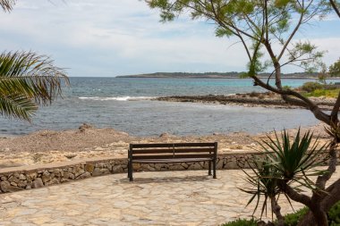 Mittelmerr güzel bir manzara üzerinde İspanyolca Balear adaya Mallorca önünde parlak mavi gökyüzü ile holiday resort Cala Millor sahilinde tek bir bankta