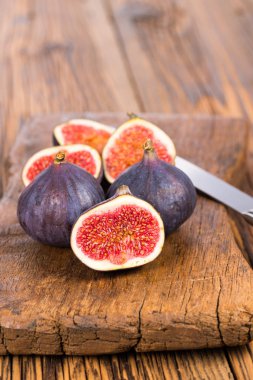 Grup tüm ve dilimlenmiş Olgun, lezzetli ve tatlılar incir eski bir rustik ahşap kesme tahtası üzerinde bir mutfak bıçağı ile