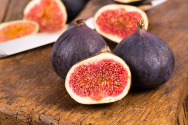 Grup tüm ve dilimlenmiş Olgun, lezzetli ve tatlılar incir eski bir rustik ahşap kesme tahtası üzerinde bir mutfak bıçağı ile