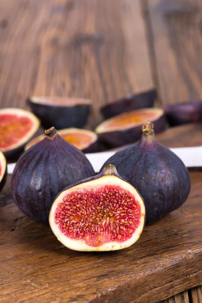 Grup tüm ve dilimlenmiş Olgun, lezzetli ve tatlılar incir kopya alanı üst resim alanında ile eski bir rustik ahşap kesme tahtası üzerinde bir mutfak bıçağı ile