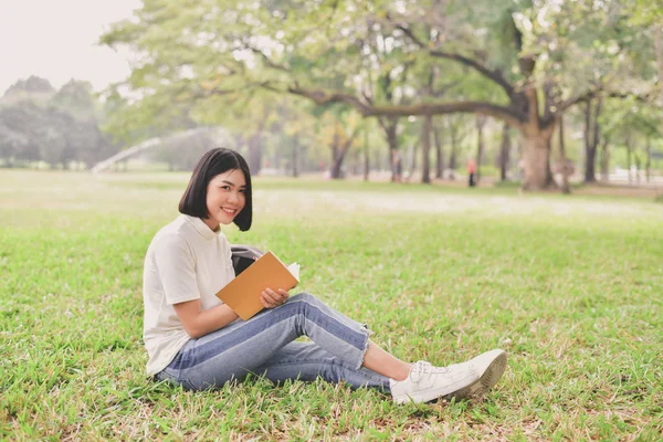 Education Concepts. Asian women reading books in the park. Beautiful women are relaxing in the park. Beautiful women are happy to read.