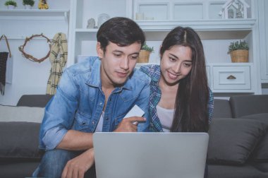 Çiftler kavramı. Aşık oturma odasında oynuyorlar. Çiftler Internet üzerinden alışveriş vardır. Aşık bir defter mutlu oynuyorlar. Oturma odasında rahatlatıcı aşıklar.