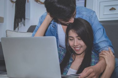 Çiftler kavramı. Aşık oturma odasında oynuyorlar. Çiftler Internet üzerinden alışveriş vardır. Aşık bir defter mutlu oynuyorlar. Oturma odasında rahatlatıcı aşıklar.