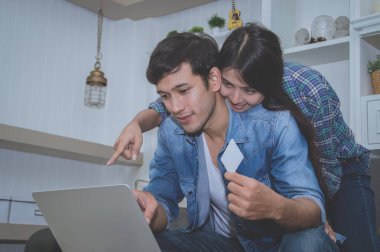 Çiftler kavramı. Aşık oturma odasında oynuyorlar. Çiftler Internet üzerinden alışveriş vardır. Aşık bir defter mutlu oynuyorlar. Oturma odasında rahatlatıcı aşıklar.