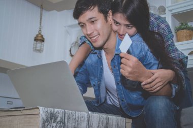 Çiftler kavramı. Aşık oturma odasında oynuyorlar. Çiftler Internet üzerinden alışveriş vardır. Aşık bir defter mutlu oynuyorlar. Oturma odasında rahatlatıcı aşıklar.