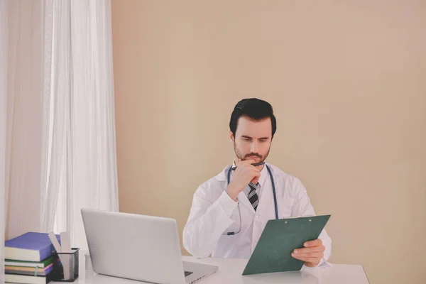 微笑的医生摆在办公室 他戴着听诊器 医务人员在医院的背景 — 图库照片