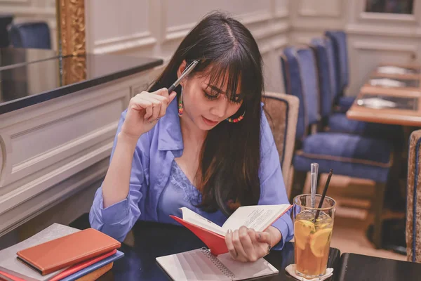 Education Concepts. Asian women are working in a restaurant. Asian women are reading a book in a restaurant.