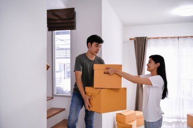 Konsept ev taşıma. Asya genç adam eşyalarını taşıyor. Genç Asyalı kadınlar eşyalarını bir kağıt kutu içinde tutuyor. Genç yeni evinde mutlu.