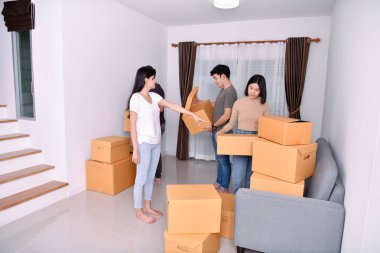 Konsept ev taşıma. Asya genç adam eşyalarını taşıyor. Genç Asyalı kadınlar eşyalarını bir kağıt kutu içinde tutuyor. Genç yeni evinde mutlu.