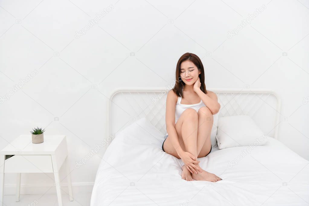 Lifestyle Concept. Beautiful asian woman is relaxing in a white bedroom. Asian girls are playing in the bedroom happily.